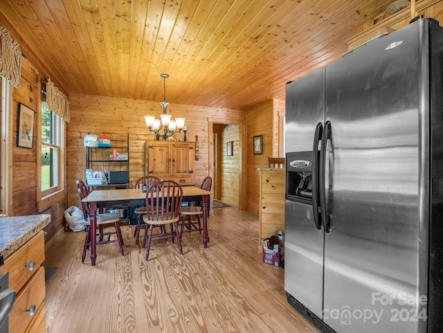 dining room featuring a chandelier, wooden ceiling, wooden walls, and light wood finished floors