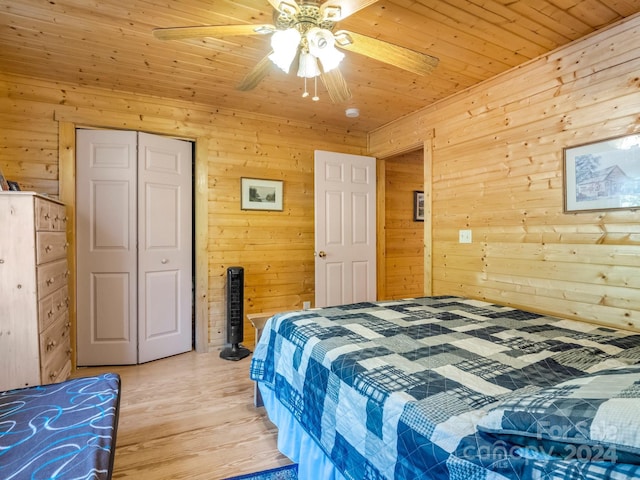 bedroom featuring a ceiling fan, wood ceiling, wood walls, light wood-style floors, and a closet