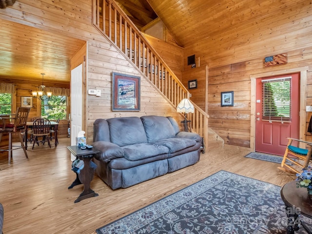 living room with stairway, an inviting chandelier, wooden walls, wood finished floors, and wooden ceiling