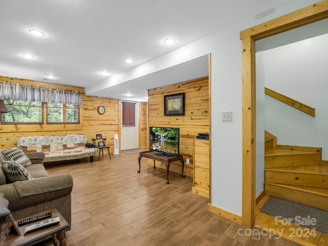 living area with recessed lighting, wooden walls, light wood finished floors, and stairs