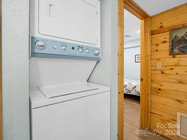 clothes washing area featuring stacked washer and dryer, laundry area, visible vents, and light wood-style flooring