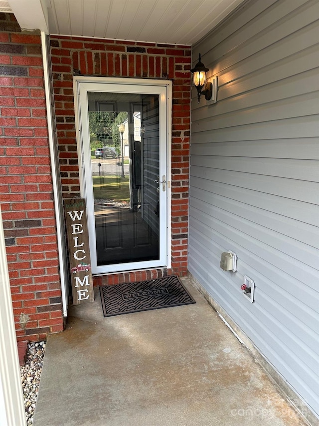 view of exterior entry featuring brick siding