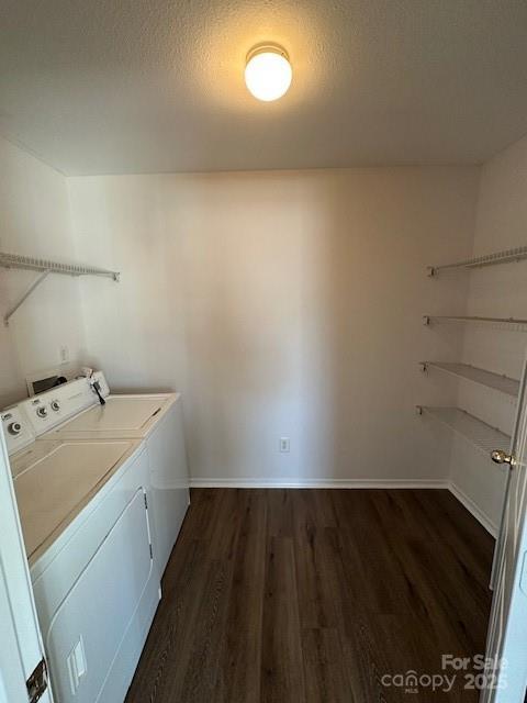 washroom with laundry area, baseboards, dark wood-type flooring, and washing machine and clothes dryer