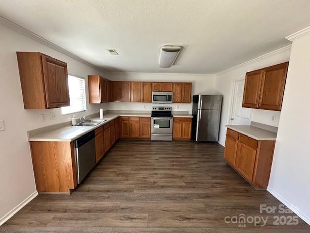 kitchen featuring stainless steel appliances, light countertops, brown cabinetry, ornamental molding, and dark wood-type flooring