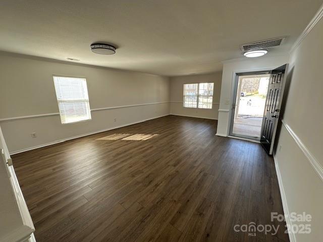 foyer with ornamental molding, dark wood-type flooring, visible vents, and baseboards