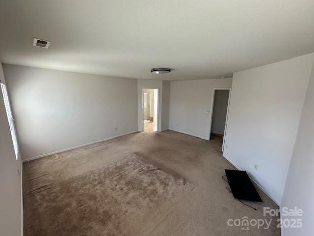 spare room featuring light colored carpet and visible vents