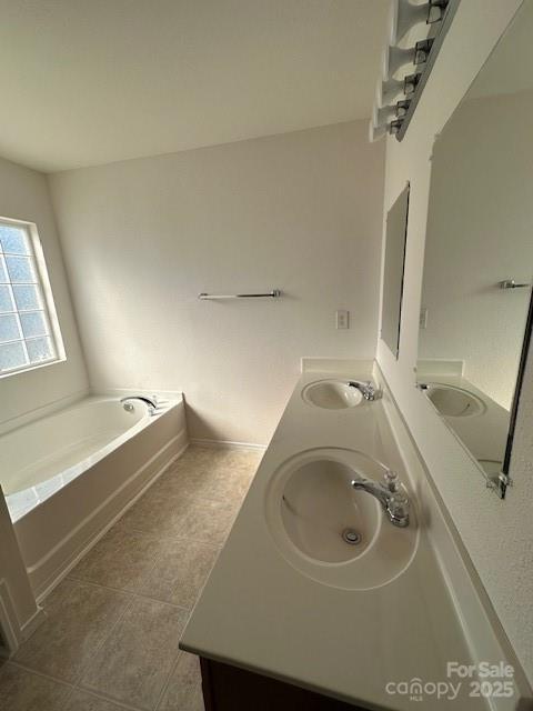 full bathroom featuring tile patterned flooring, a garden tub, a sink, and double vanity