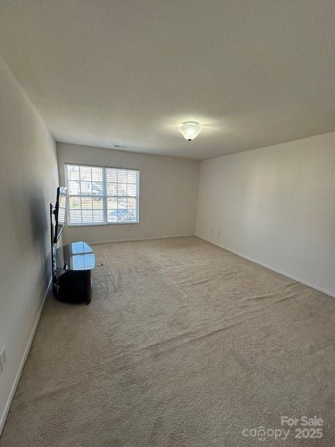 empty room featuring carpet and baseboards