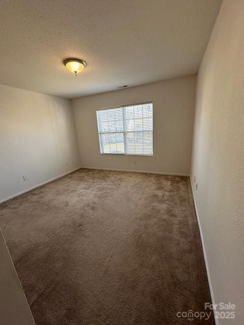 spare room with carpet flooring, a textured ceiling, and baseboards