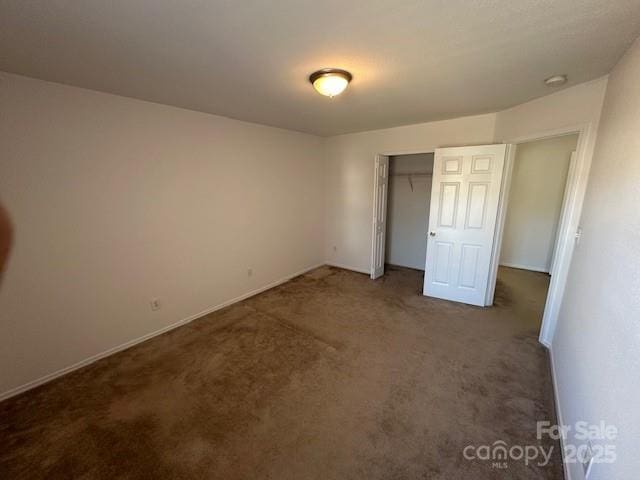 unfurnished bedroom with a closet and dark carpet