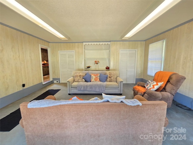 living room with a textured ceiling, carpet flooring, and wood walls