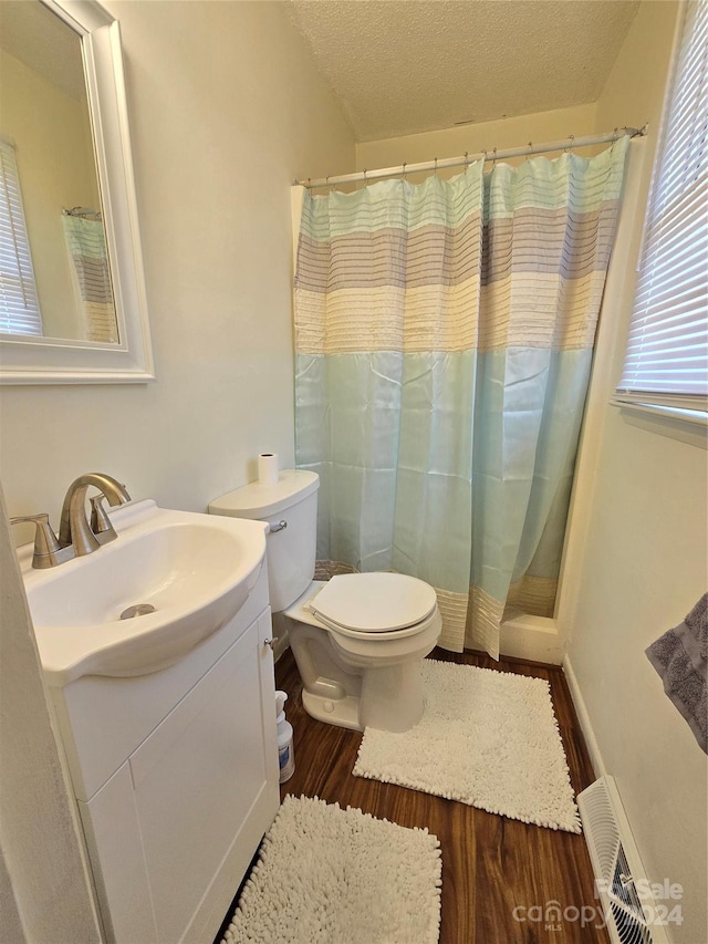 bathroom featuring a textured ceiling, toilet, hardwood / wood-style flooring, vanity, and curtained shower