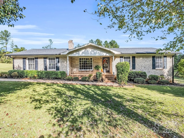 ranch-style house with a chimney, a front lawn, and brick siding