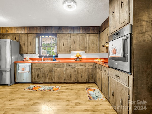 kitchen featuring light wood-type flooring, a textured ceiling, sink, and stainless steel appliances