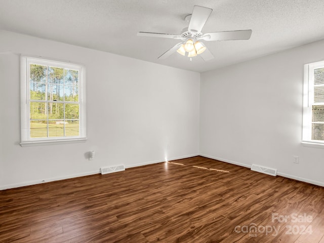 empty room with a textured ceiling, dark wood-type flooring, and ceiling fan