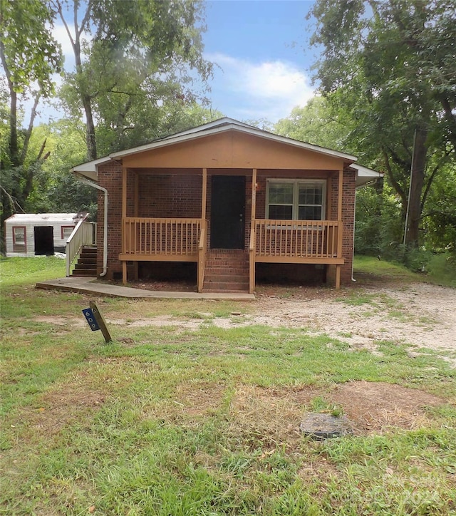 view of front of home with a front yard, a porch, and brick siding