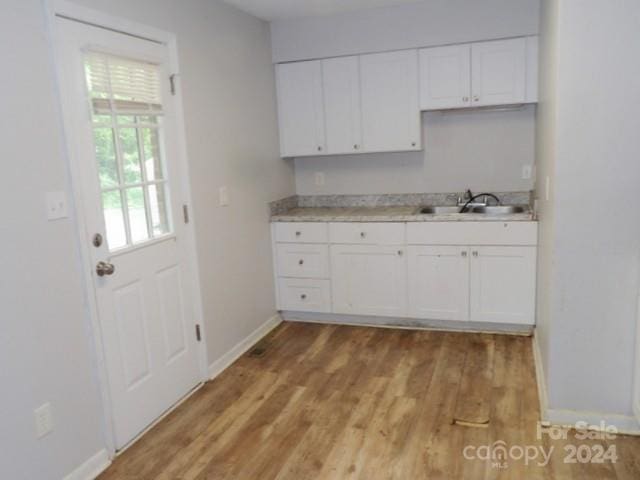 kitchen featuring light wood finished floors, baseboards, white cabinetry, and light countertops