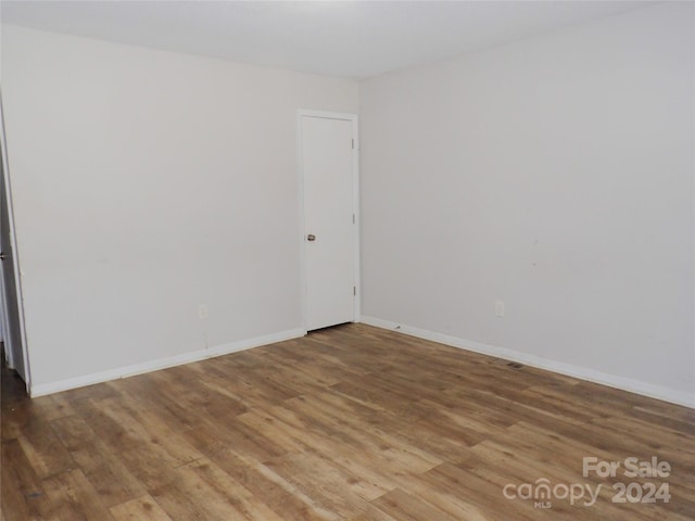 spare room with baseboards and wood finished floors