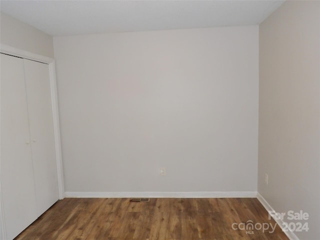 spare room with wood finished floors, visible vents, and baseboards