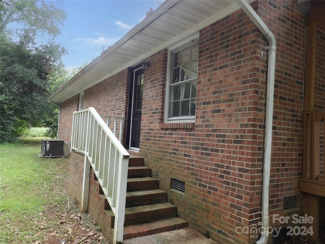 view of side of property with crawl space, cooling unit, and brick siding