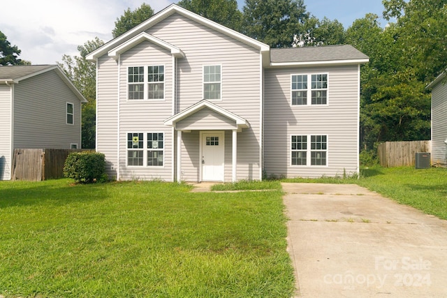 traditional home featuring a front yard, central AC unit, and fence