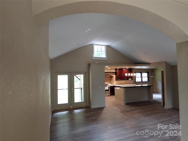 unfurnished living room featuring french doors, vaulted ceiling, a wealth of natural light, and dark hardwood / wood-style floors