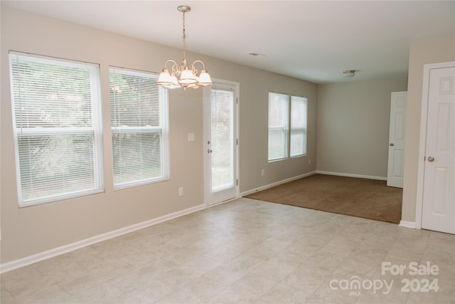 unfurnished room featuring plenty of natural light and a chandelier