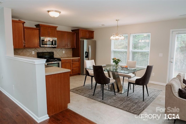 kitchen featuring light wood-type flooring, a chandelier, tasteful backsplash, hanging light fixtures, and stainless steel appliances