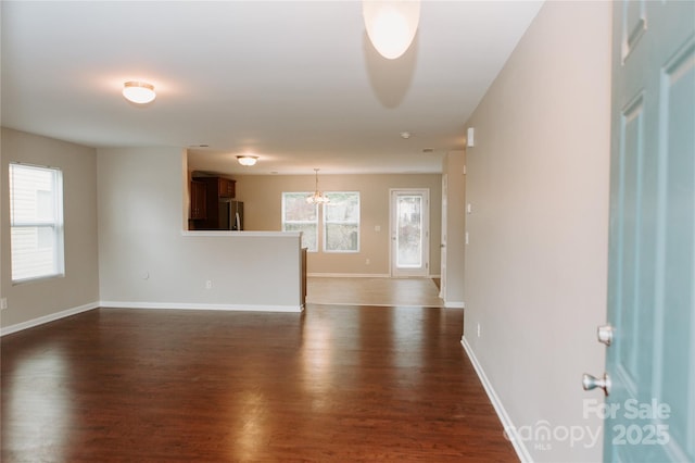 spare room with baseboards and dark wood-style flooring