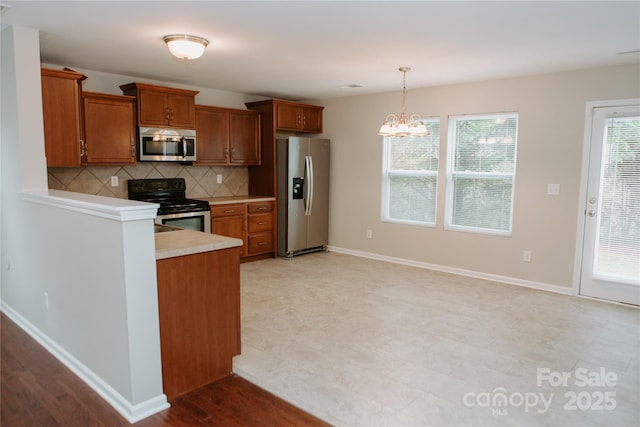 kitchen with light countertops, decorative backsplash, hanging light fixtures, a notable chandelier, and appliances with stainless steel finishes