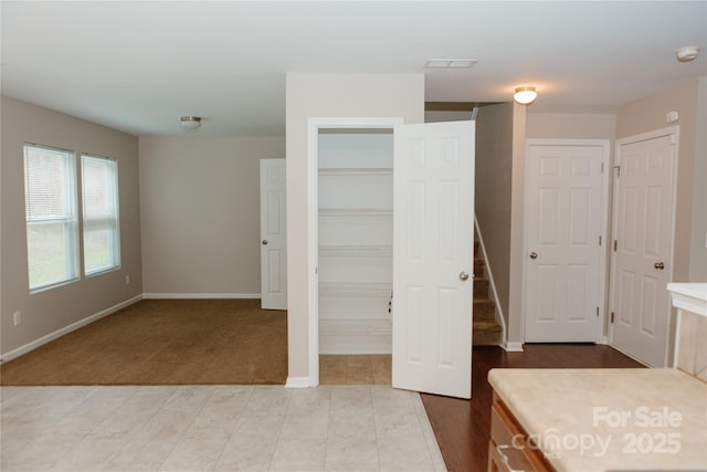 unfurnished bedroom featuring baseboards, wood finished floors, carpet floors, and a spacious closet