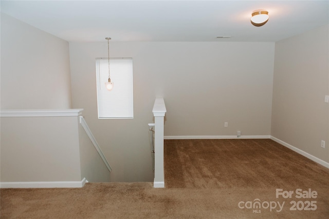 carpeted empty room featuring baseboards and visible vents