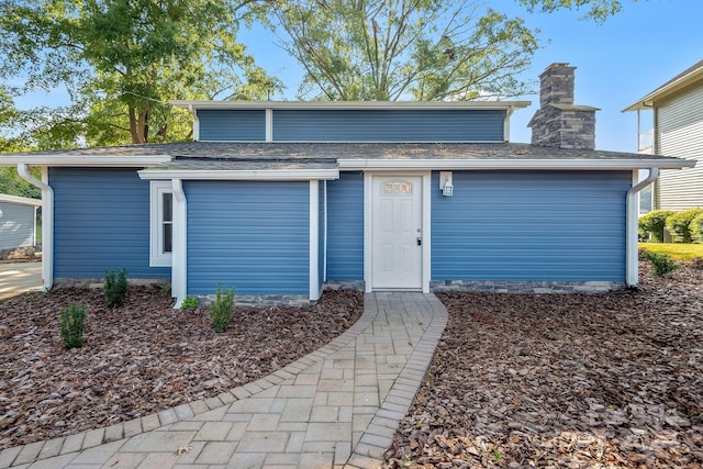 exterior space with a shingled roof and a chimney