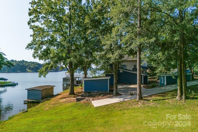 exterior space featuring an outbuilding, a water view, a lawn, and a storage shed