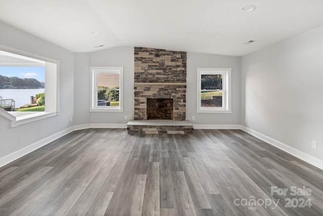 unfurnished living room featuring lofted ceiling, a water view, a fireplace, and dark hardwood / wood-style floors