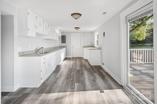 kitchen with dark wood-type flooring, white cabinets, light stone countertops, and sink