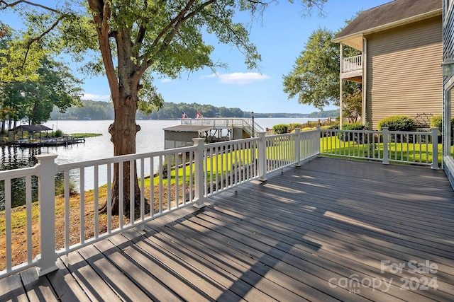 wooden terrace featuring a water view and a lawn