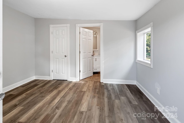 unfurnished bedroom with dark wood-type flooring and connected bathroom