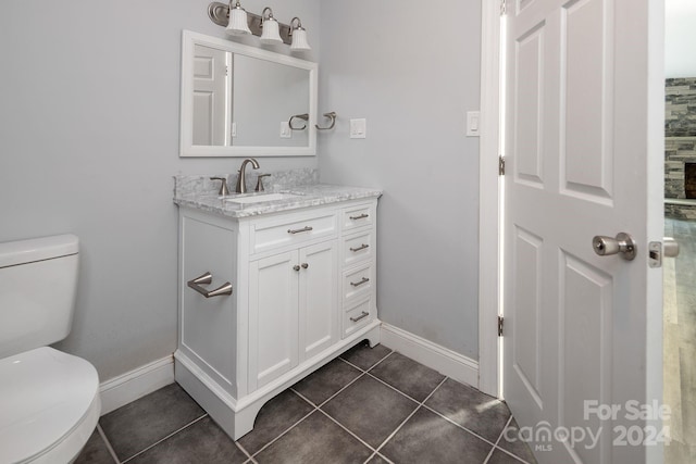 bathroom featuring toilet, tile patterned floors, baseboards, and vanity