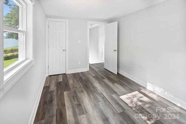 unfurnished bedroom with baseboards and dark wood-style flooring