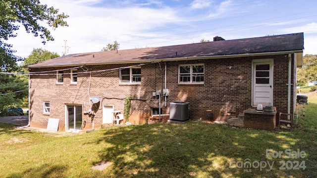 rear view of property featuring central AC and a yard