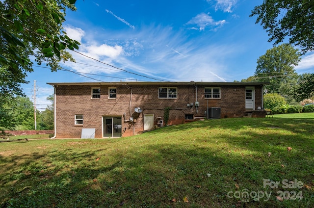 rear view of property with central air condition unit and a yard