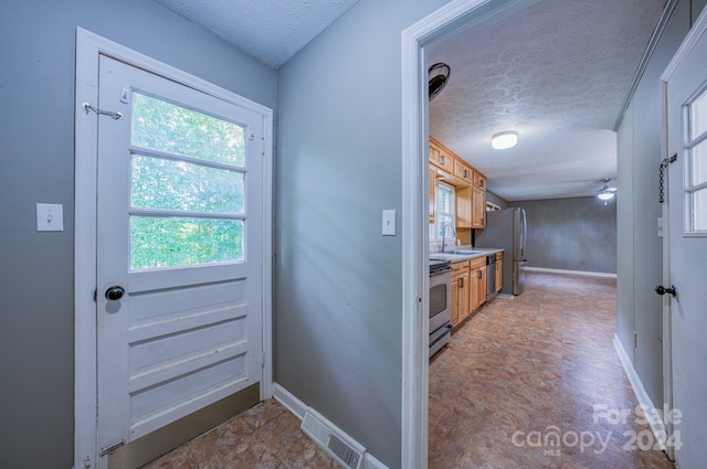 doorway to outside featuring a textured ceiling, sink, and ceiling fan