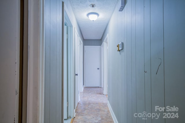 corridor with a textured ceiling and wooden walls