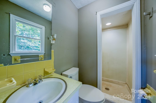 bathroom featuring toilet, vanity, tasteful backsplash, a textured ceiling, and a shower