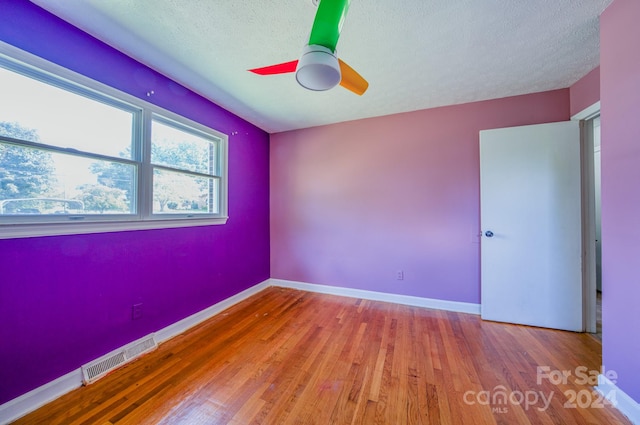 unfurnished room with a textured ceiling, wood-type flooring, and ceiling fan