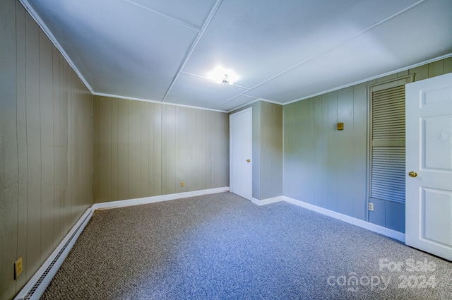 interior space featuring wood walls, carpet flooring, and baseboard heating