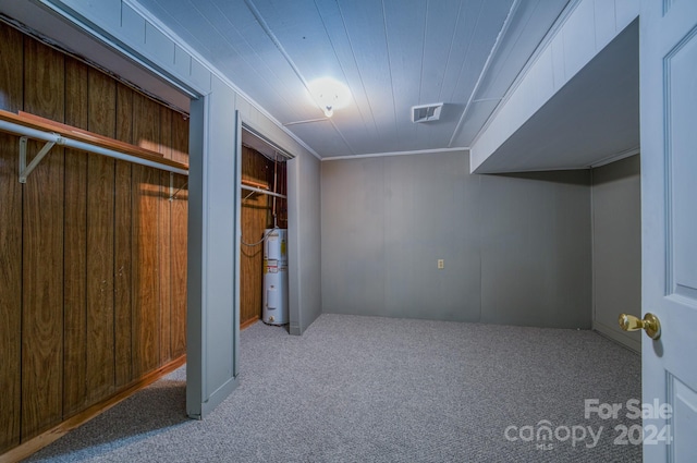 unfurnished bedroom featuring ornamental molding, water heater, wood walls, and carpet flooring