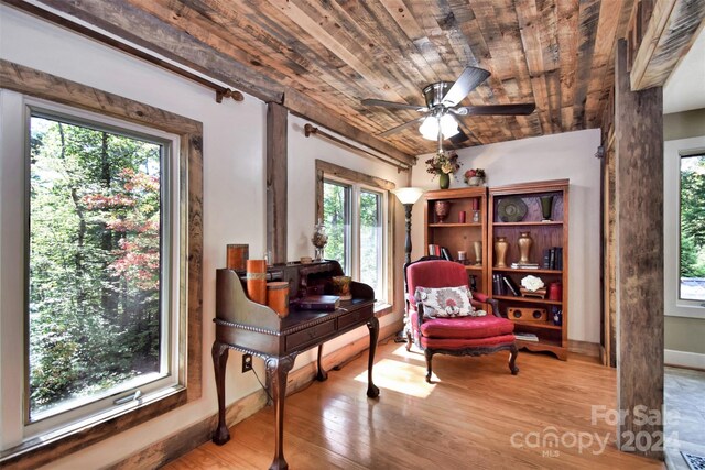 living area with light hardwood / wood-style flooring, ceiling fan, and wooden ceiling