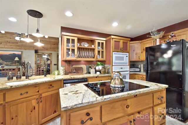 kitchen featuring pendant lighting, sink, black appliances, a center island, and light stone countertops